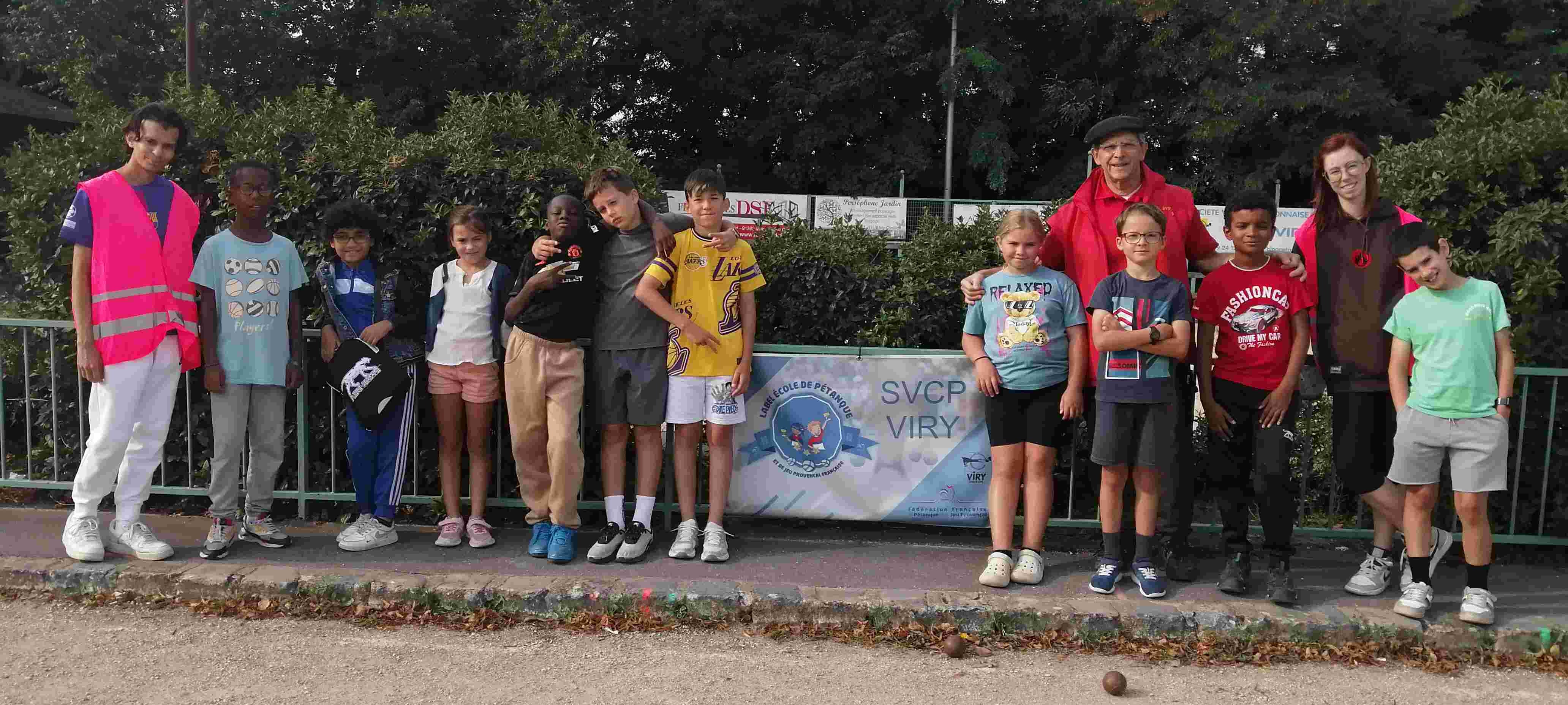 Les encadrants Hamza, notre Joël et Alexane avec les dix enfants de part et d'autre de la banderole  "École de pétanque SVP VIRY"